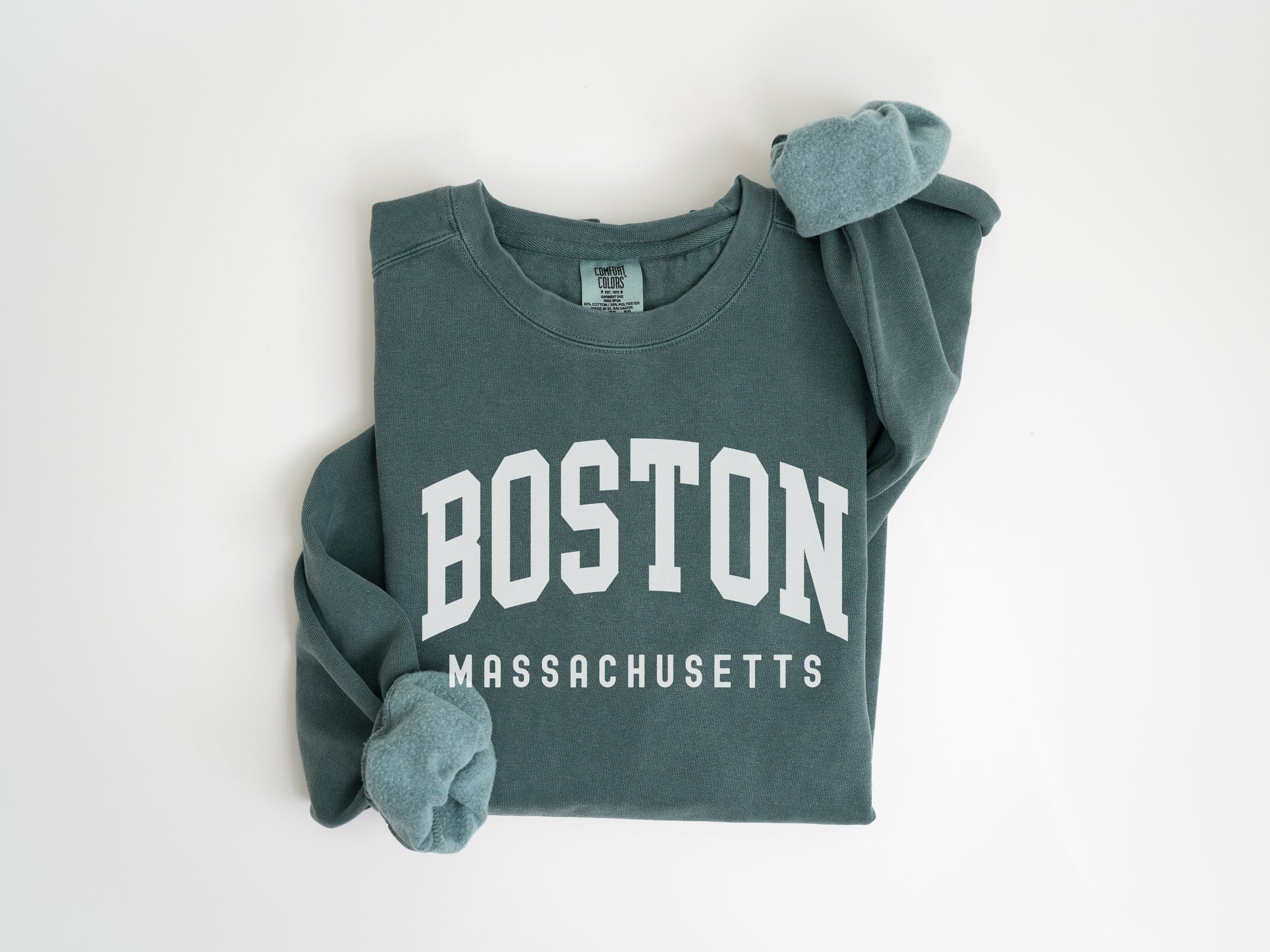 a boston massachusetts sweatshirt laying on top of a white wall