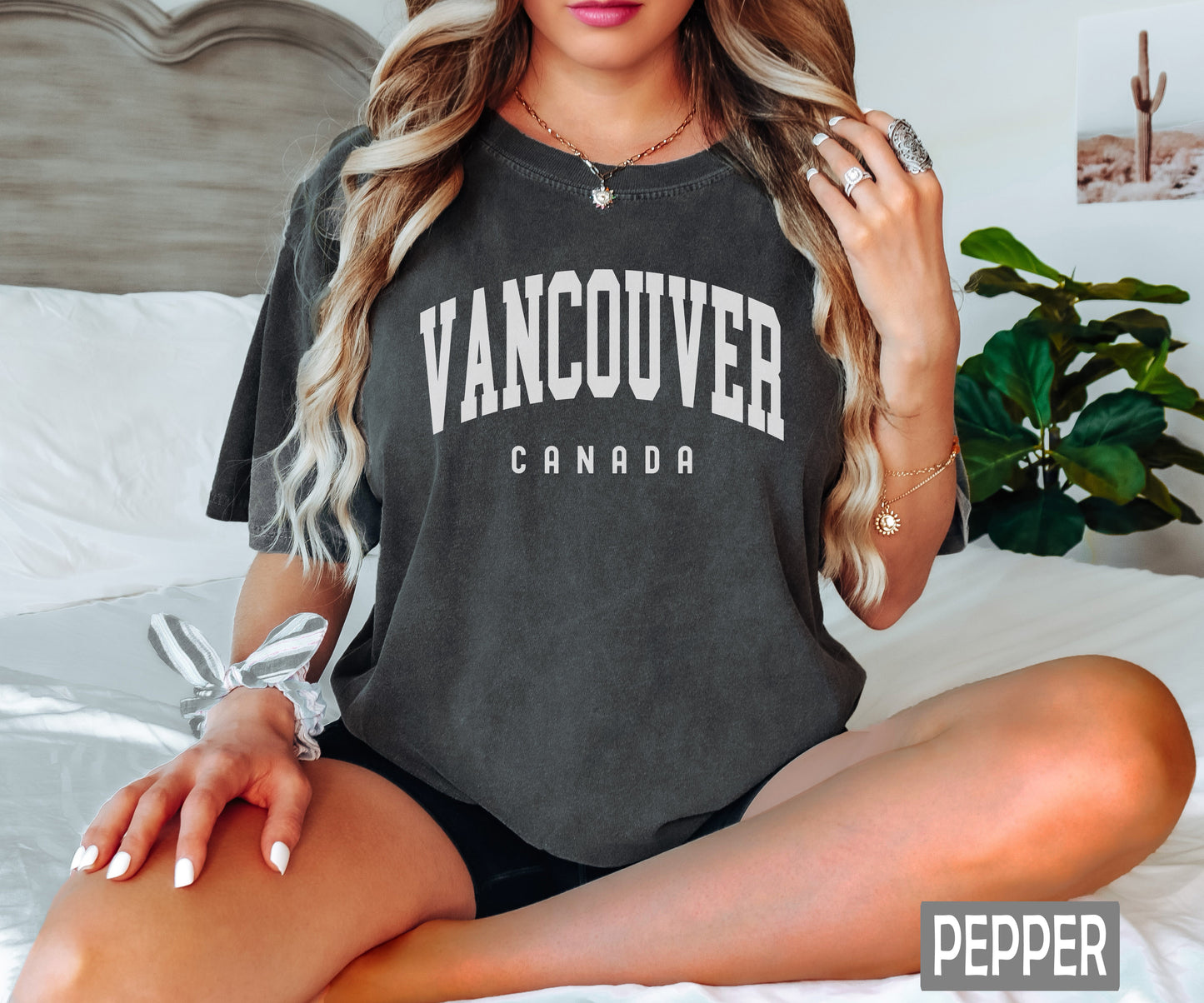 a woman sitting on a bed wearing a vancouver shirt