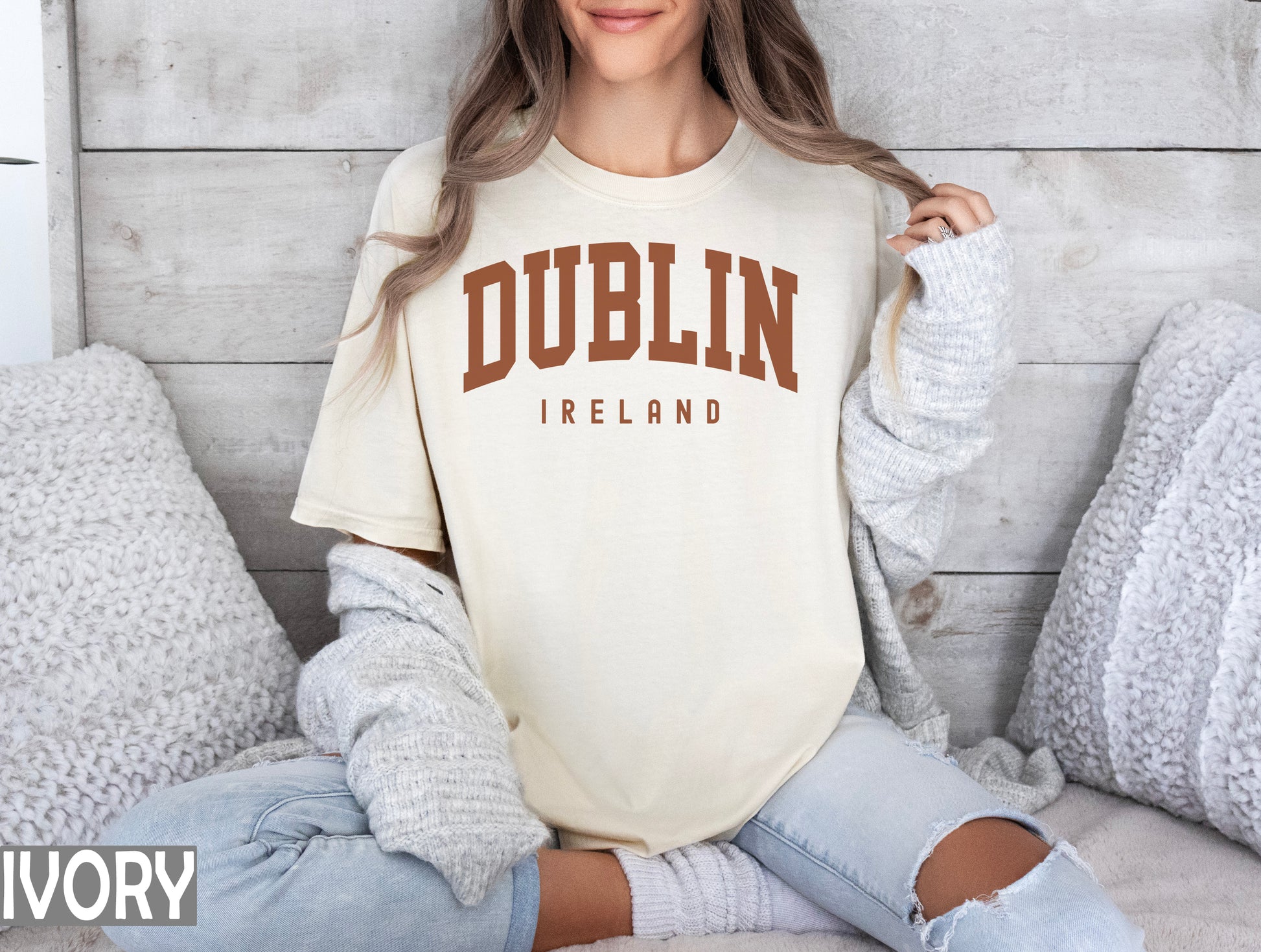 a woman sitting on a bed wearing a dublin t - shirt