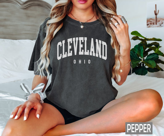 a woman sitting on a bed wearing a cleveland shirt