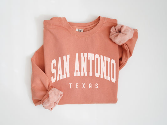 an orange sweatshirt with a pink bow on it