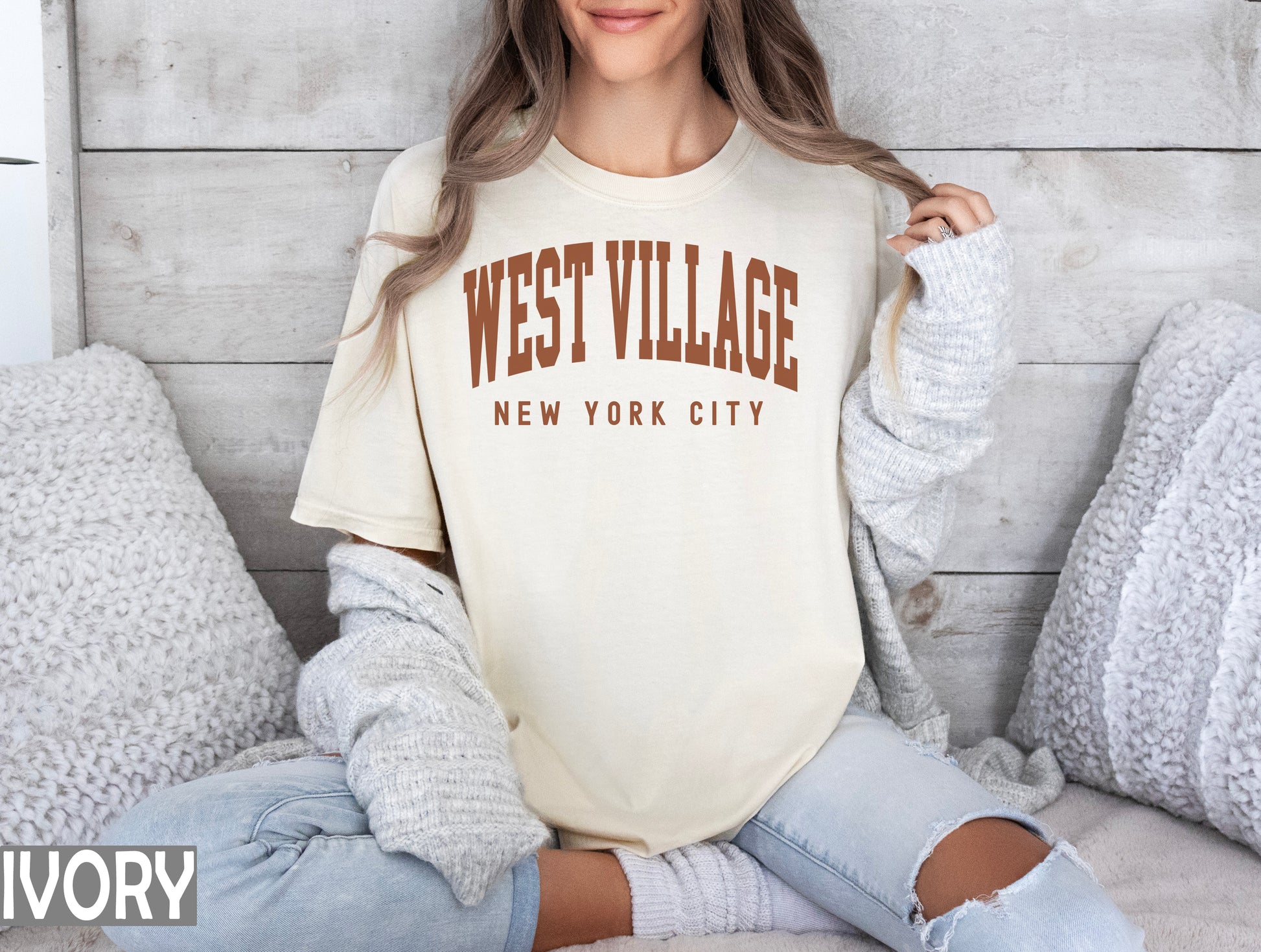 a woman sitting on a bed wearing a west village t - shirt