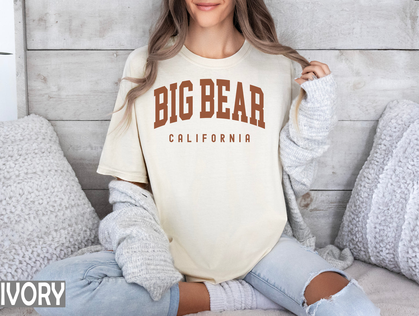 a woman sitting on a bed wearing a big bear california t - shirt