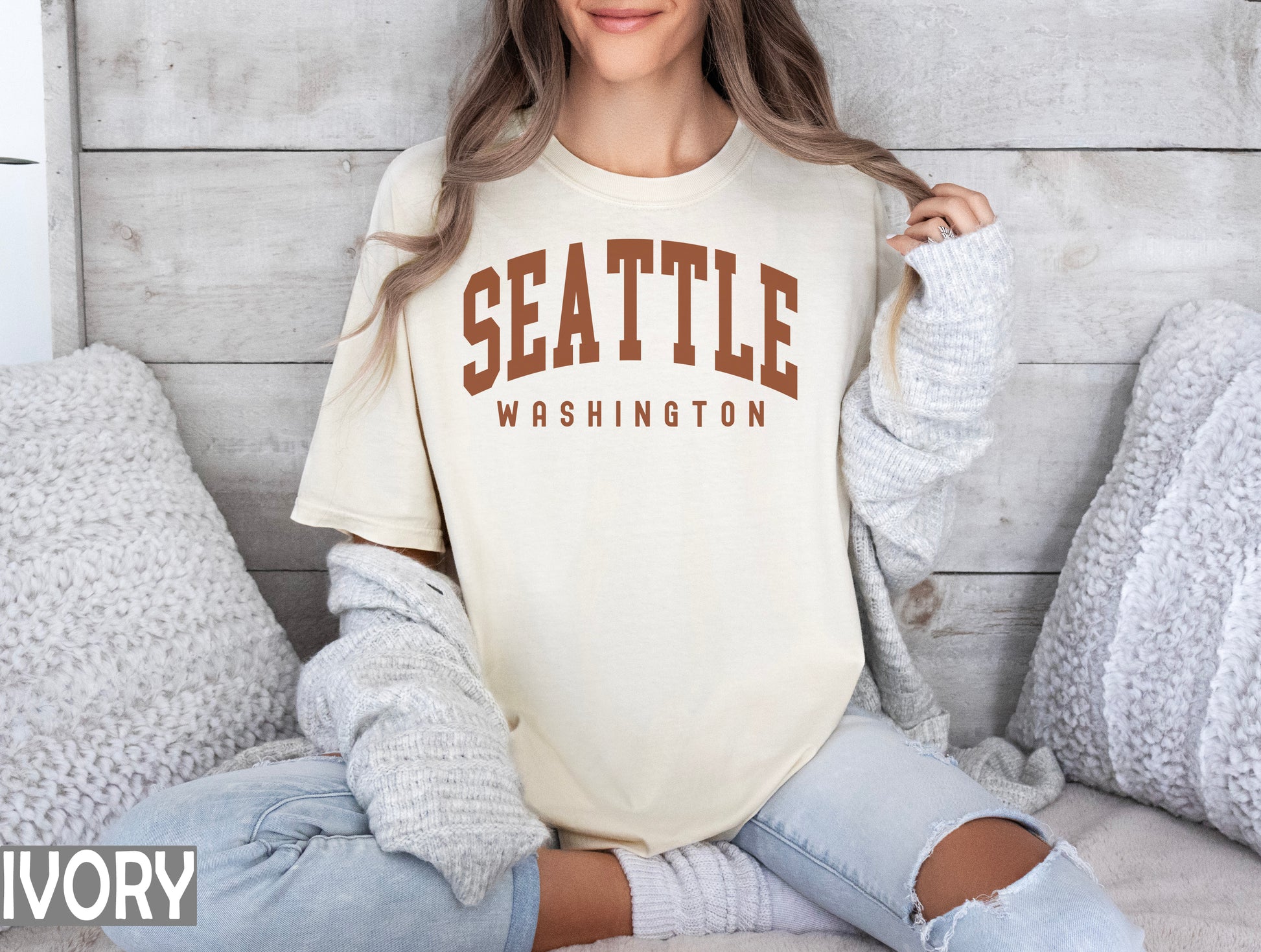 a woman sitting on a bed wearing a shirt that says seattle