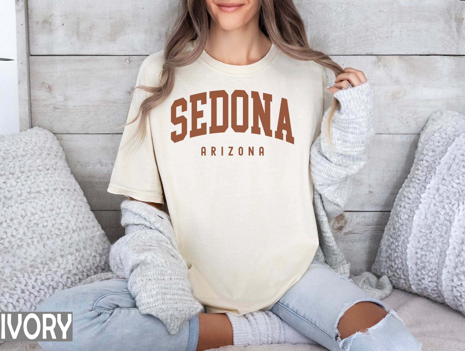 a woman sitting on a bed wearing a sedona shirt