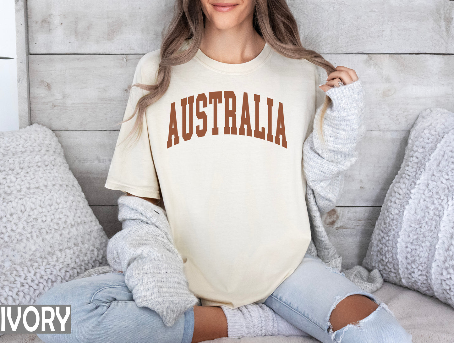 a woman sitting on a bed wearing a shirt that says australia