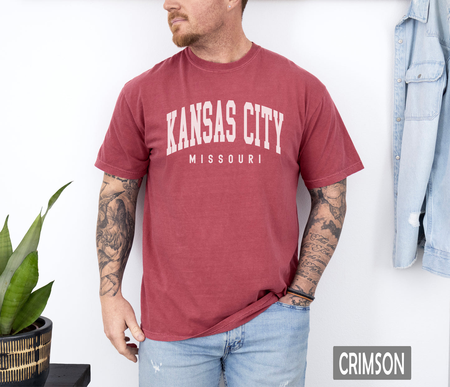 a man wearing a kansas city t - shirt standing in front of a wall