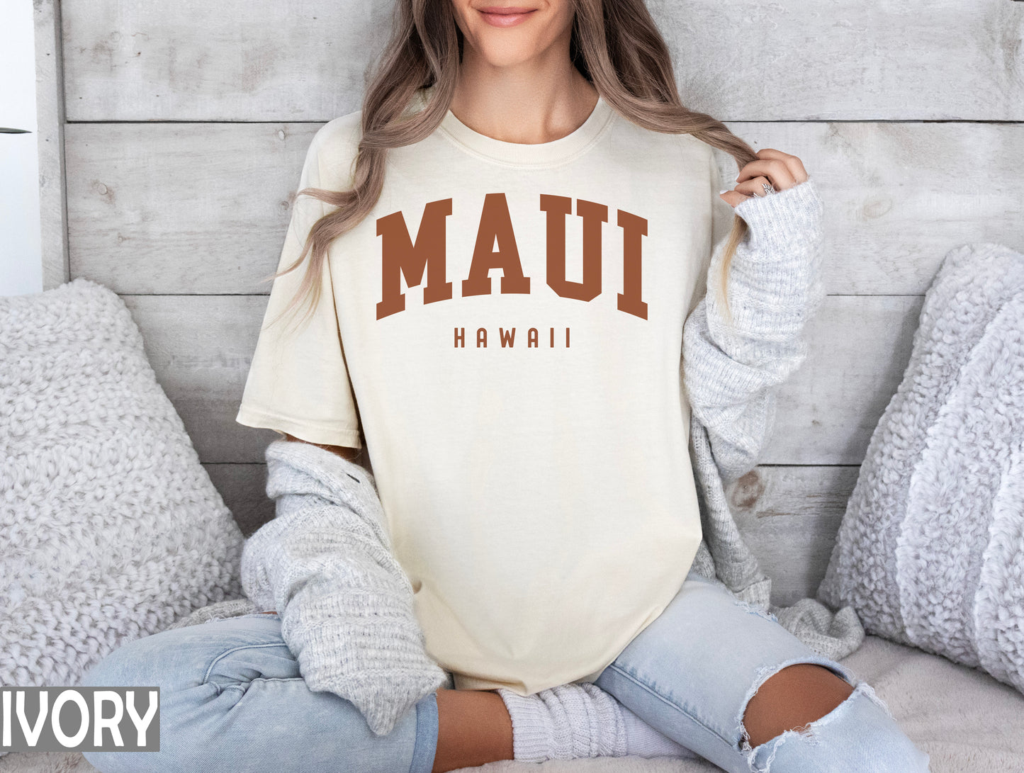 a woman sitting on a bed wearing a mau shirt