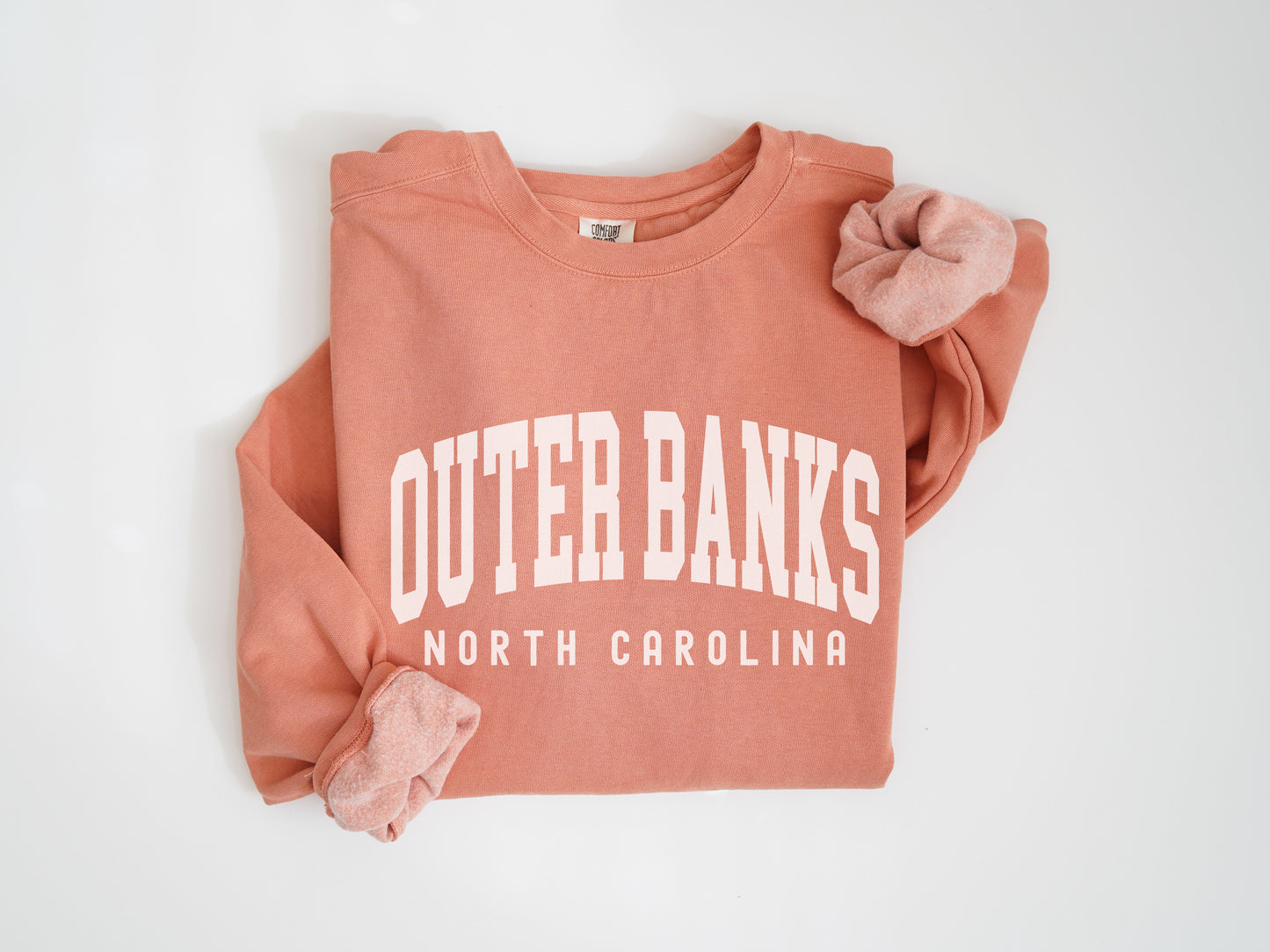 an orange sweatshirt with a pink bow on it