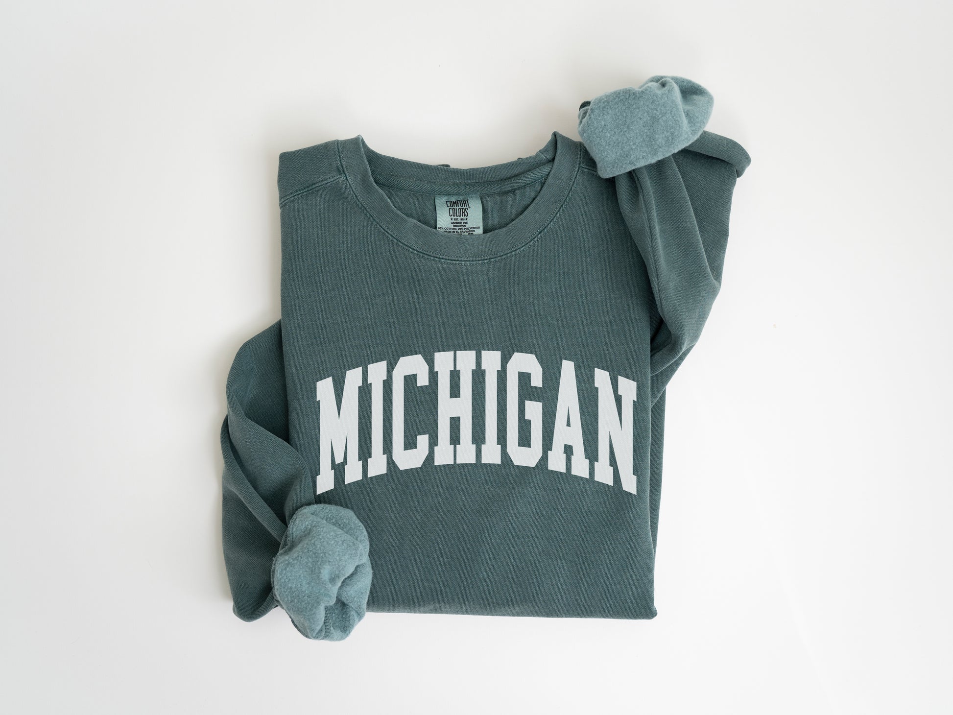 a sweatshirt with michigan on it is laying on a white surface