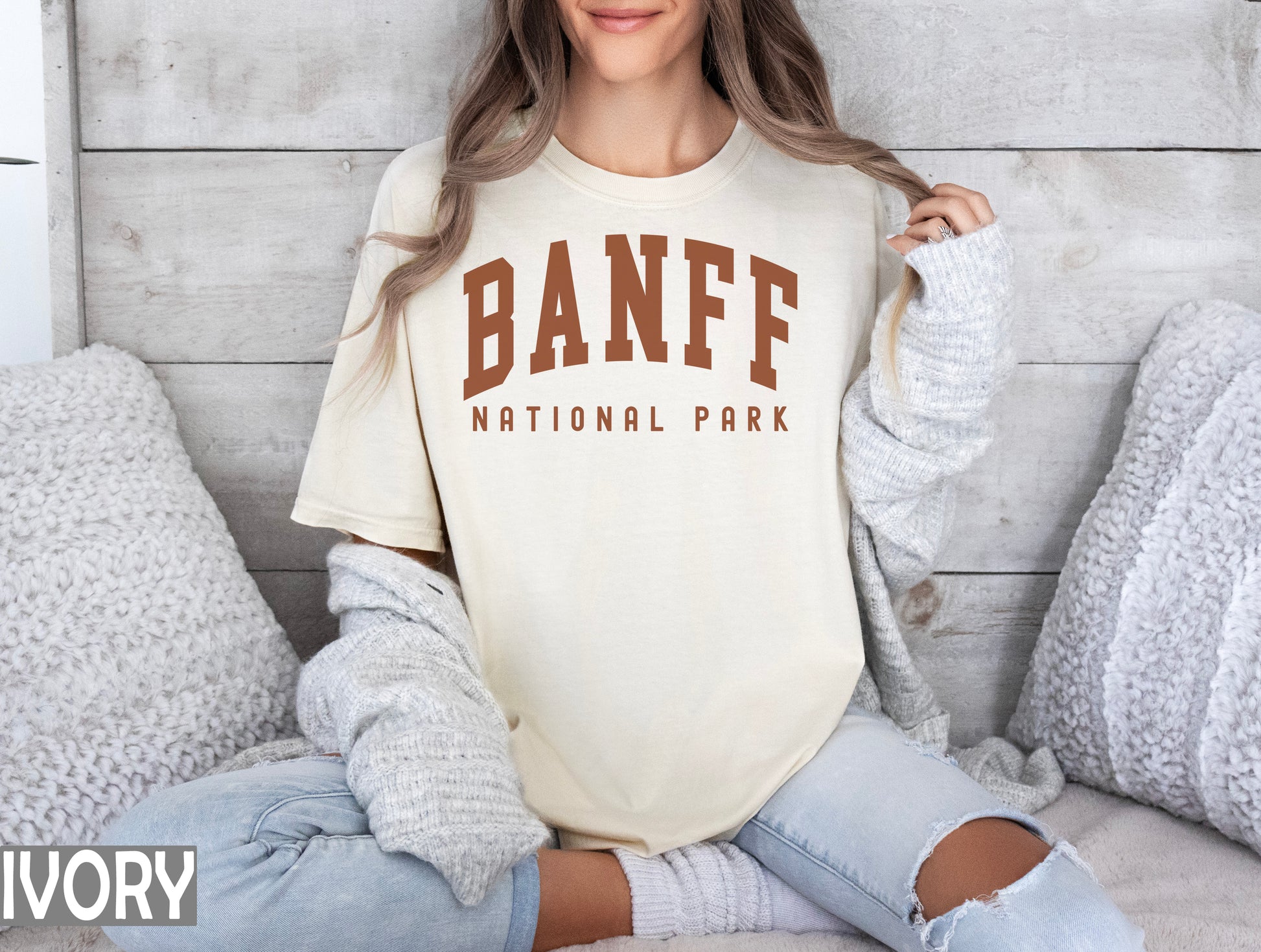 a woman sitting on a bed wearing a banff national park shirt