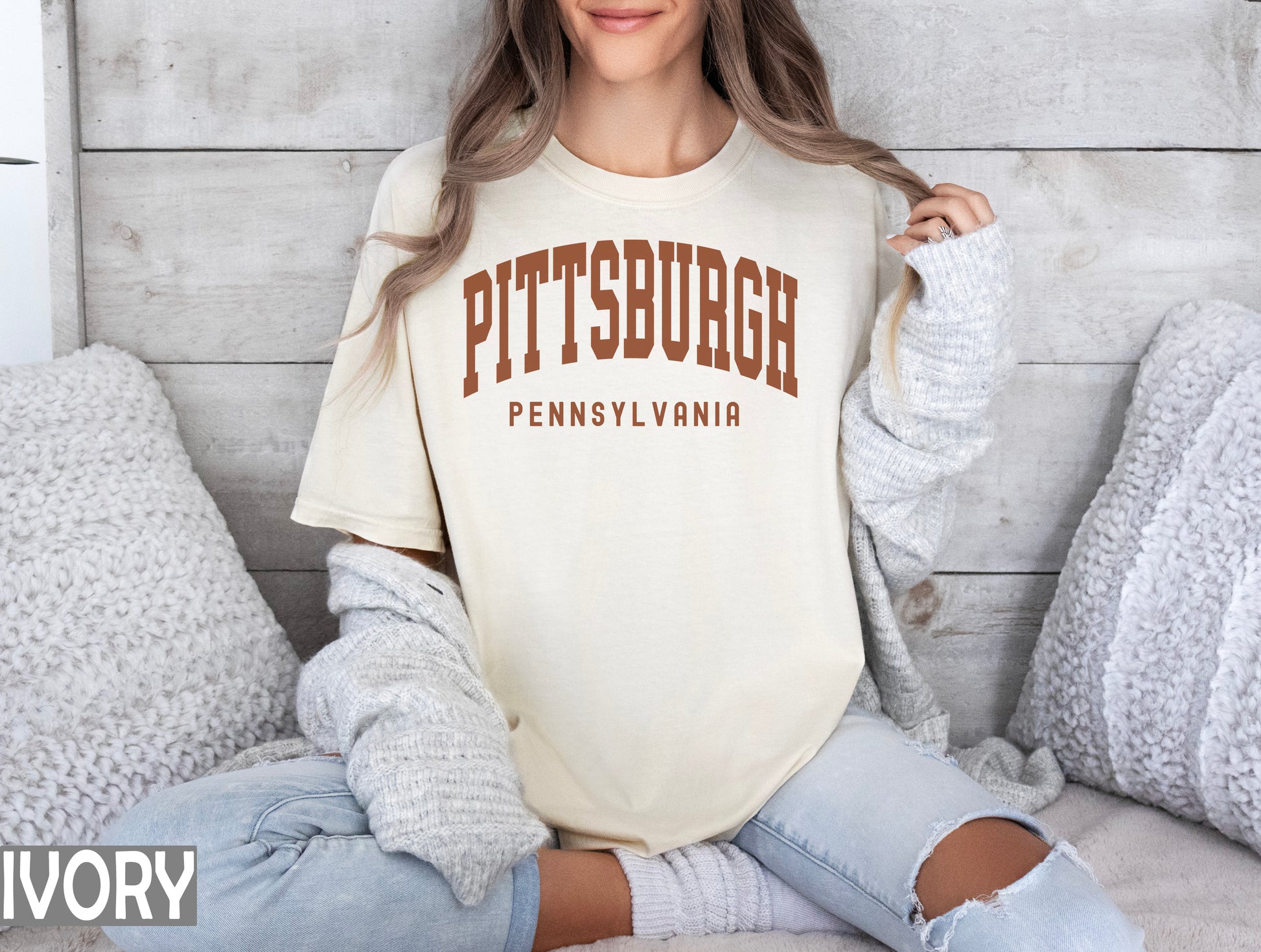 a woman sitting on a bed wearing a pittsburgh shirt