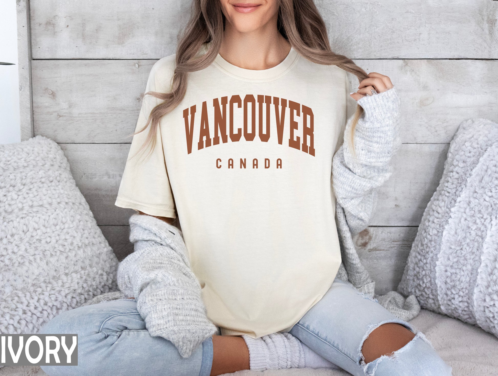 a woman sitting on a bed wearing a vancouver t - shirt