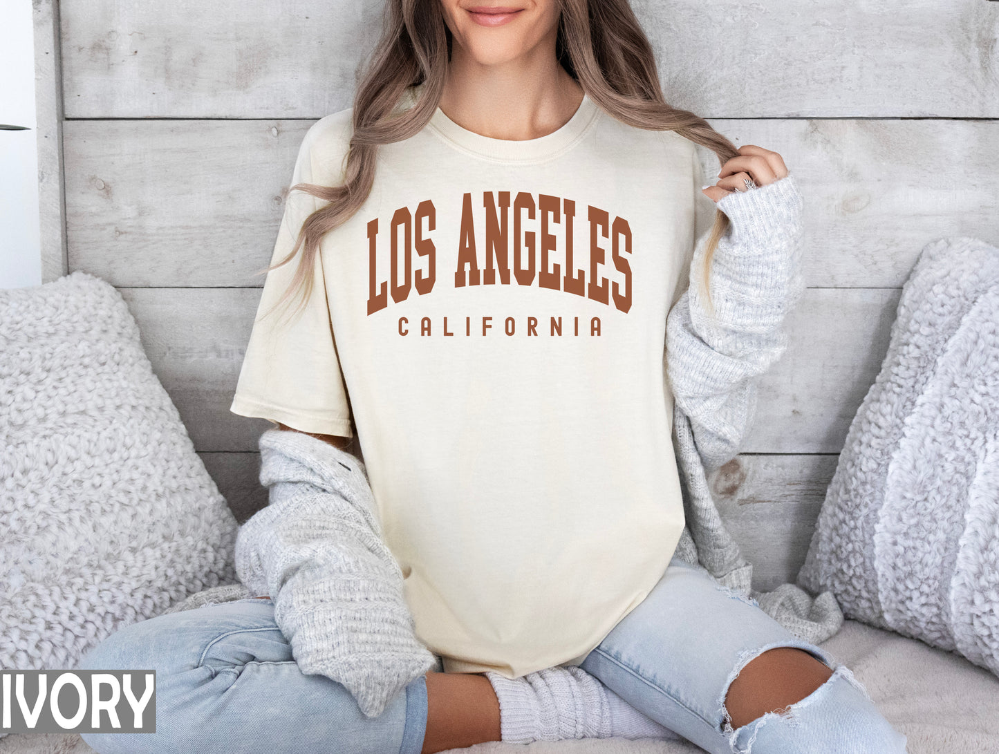 a woman sitting on a bed wearing a los angeles california t - shirt