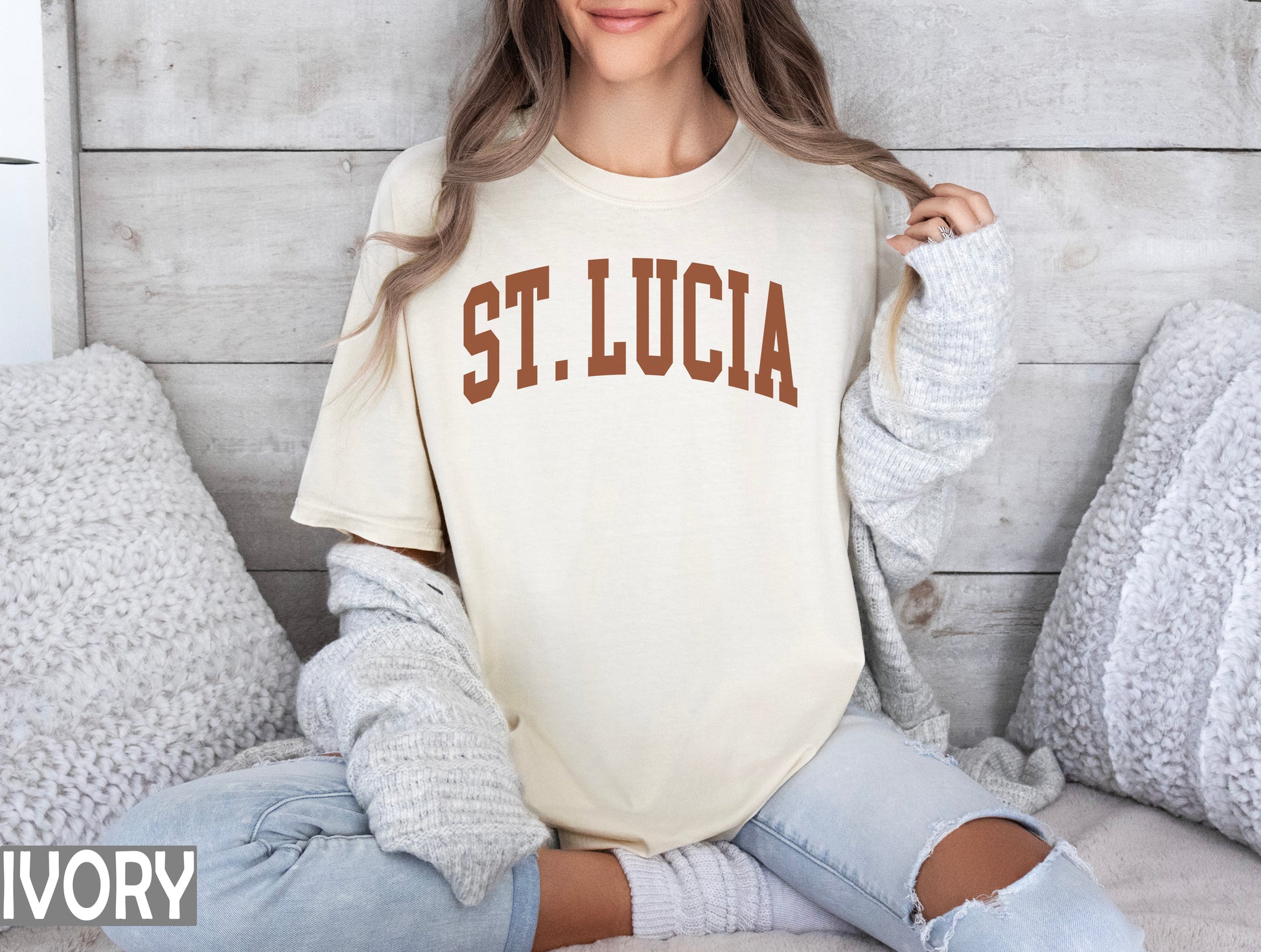 a woman sitting on a bed wearing a st lucia shirt