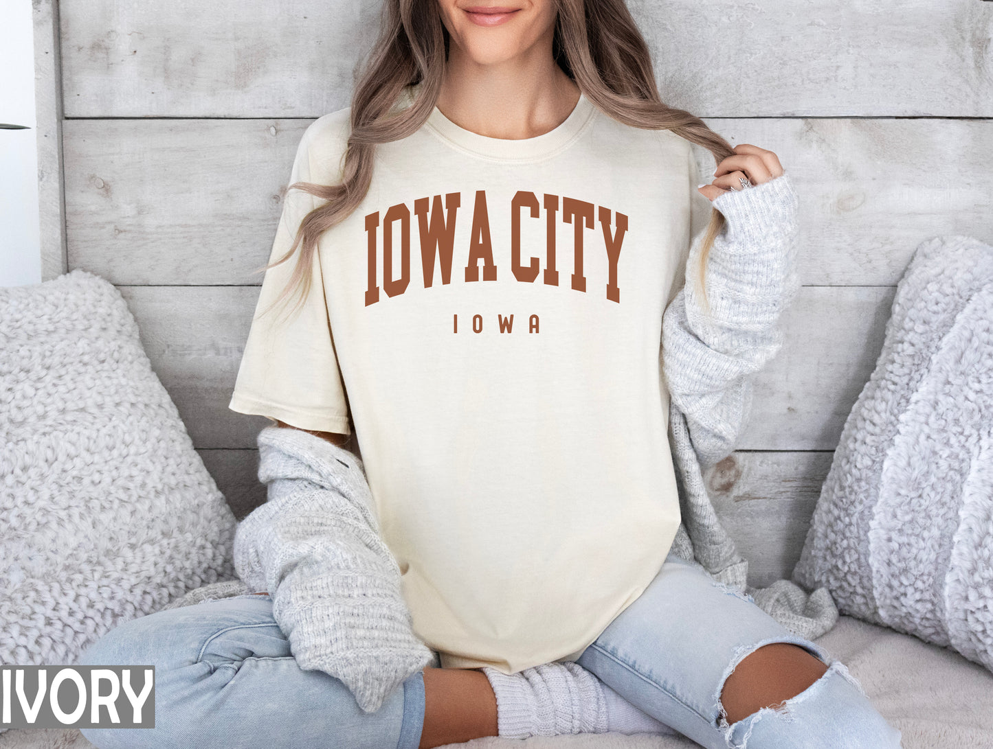 a woman sitting on a bed wearing a t - shirt that says iowa city