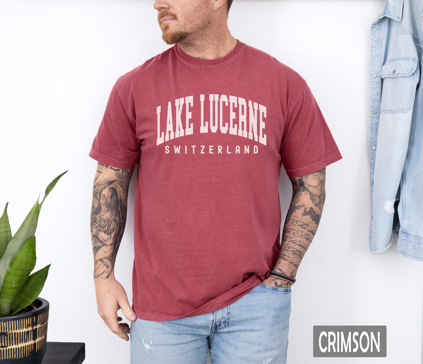 a man wearing a lake lucerne t - shirt standing in front of a wall