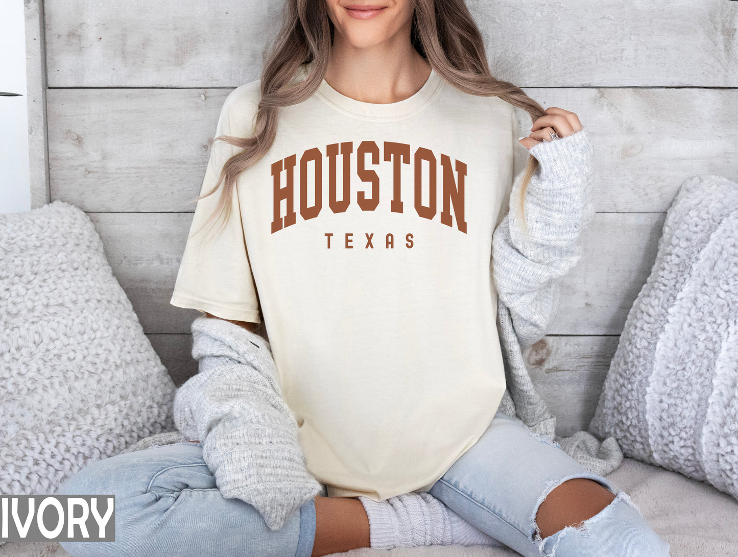 a woman sitting on a bed wearing a houston texas shirt