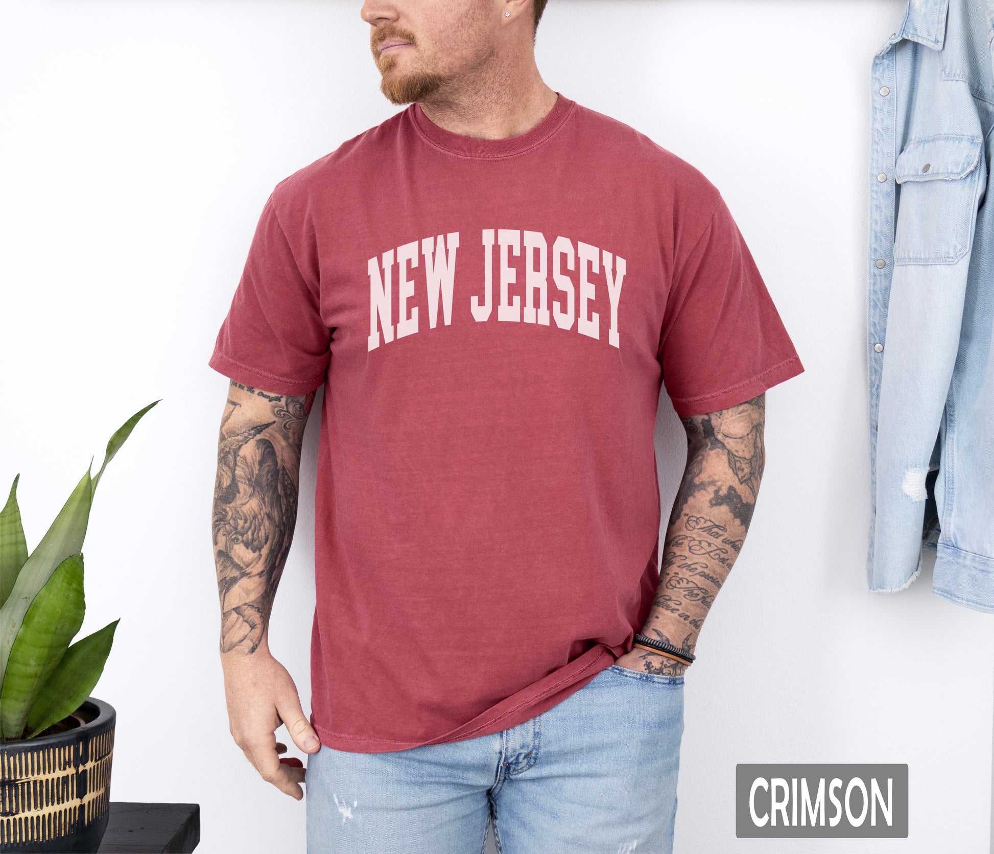 a man wearing a new jersey shirt standing next to a plant