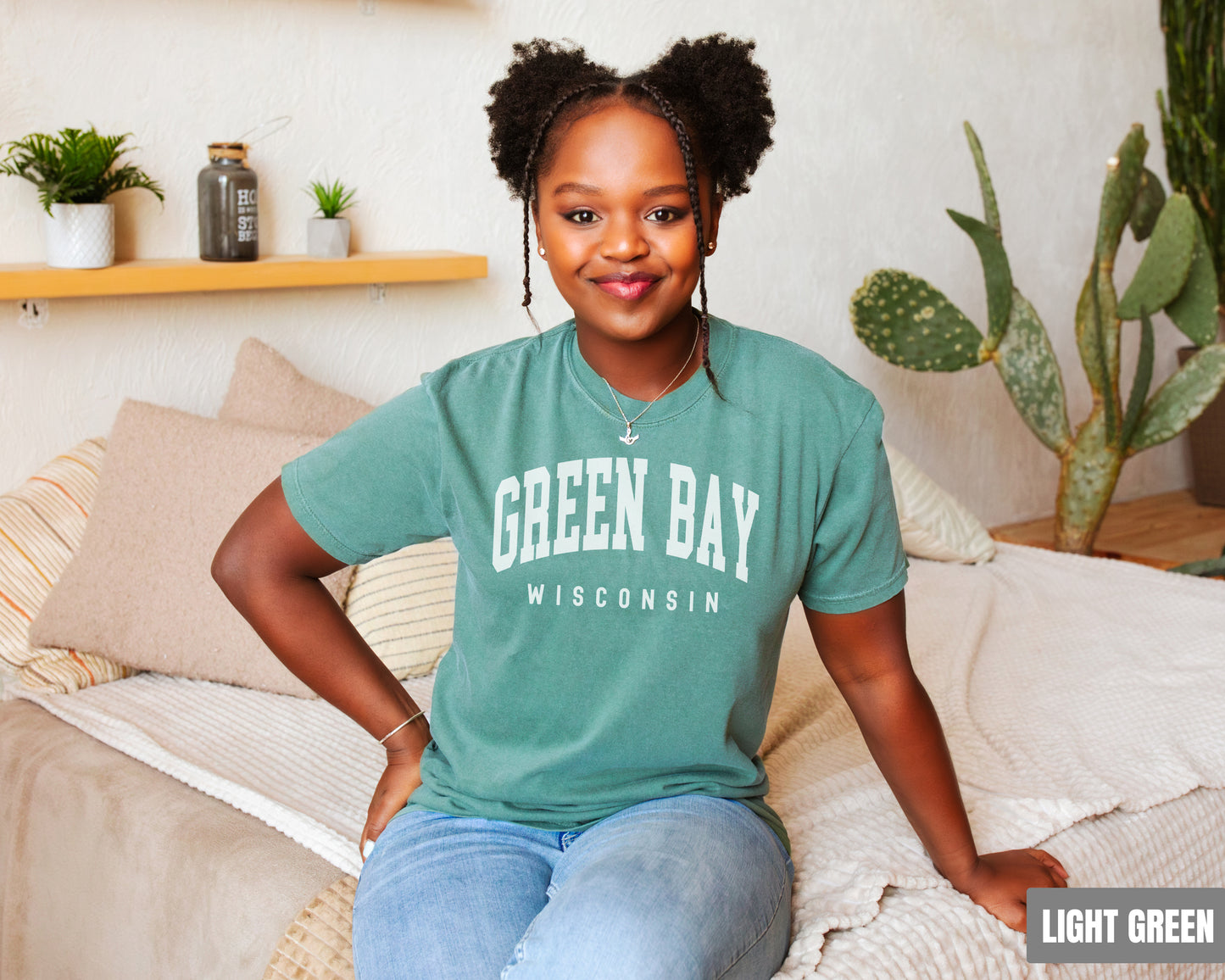 a woman sitting on top of a bed wearing a green bay shirt