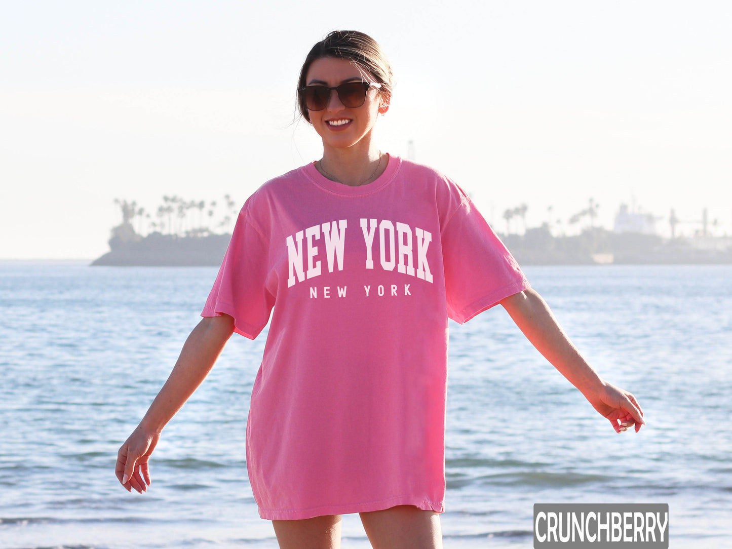 a woman in a pink new york t - shirt on the beach