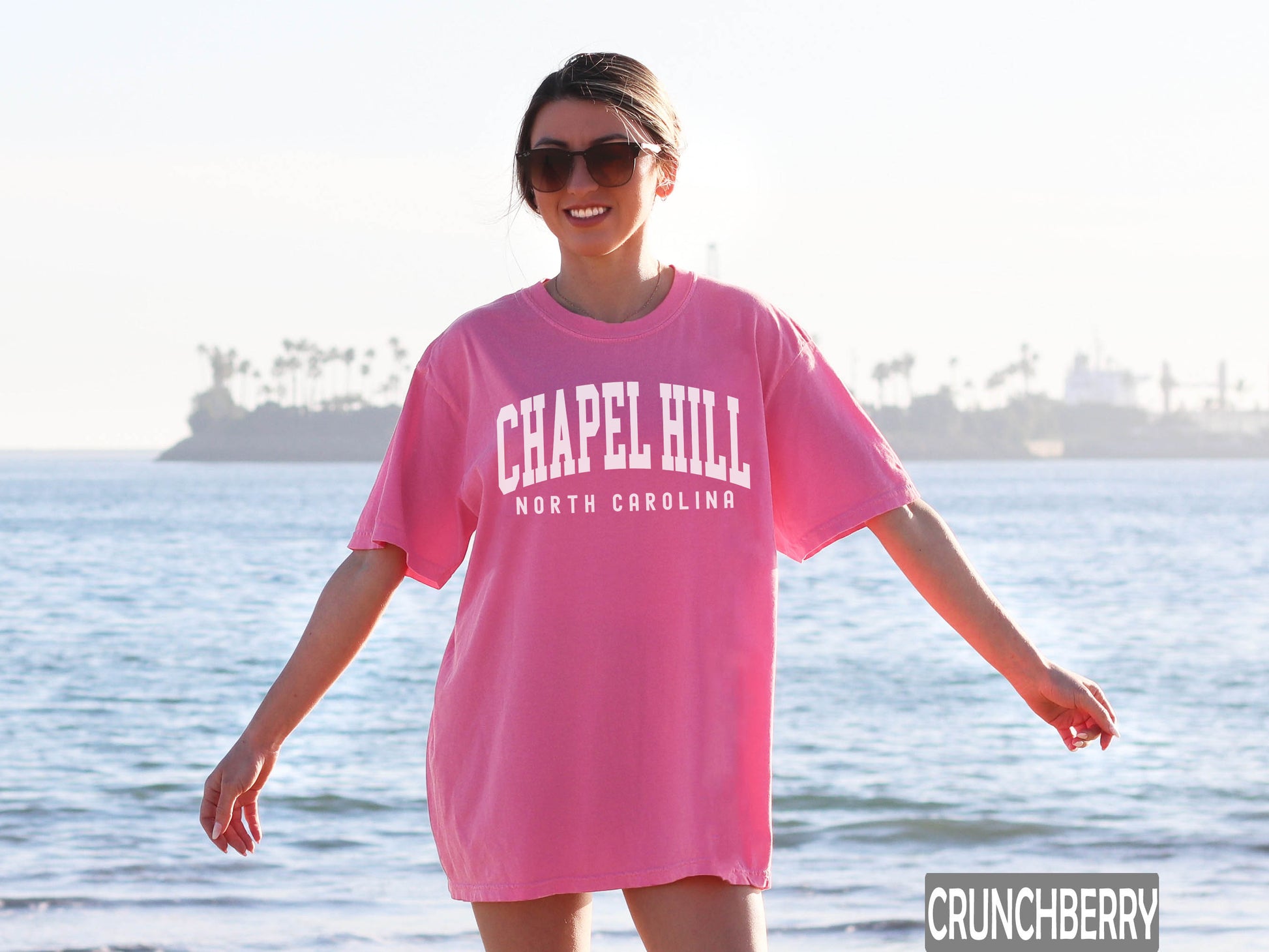 a woman in a pink capel hill shirt on the beach