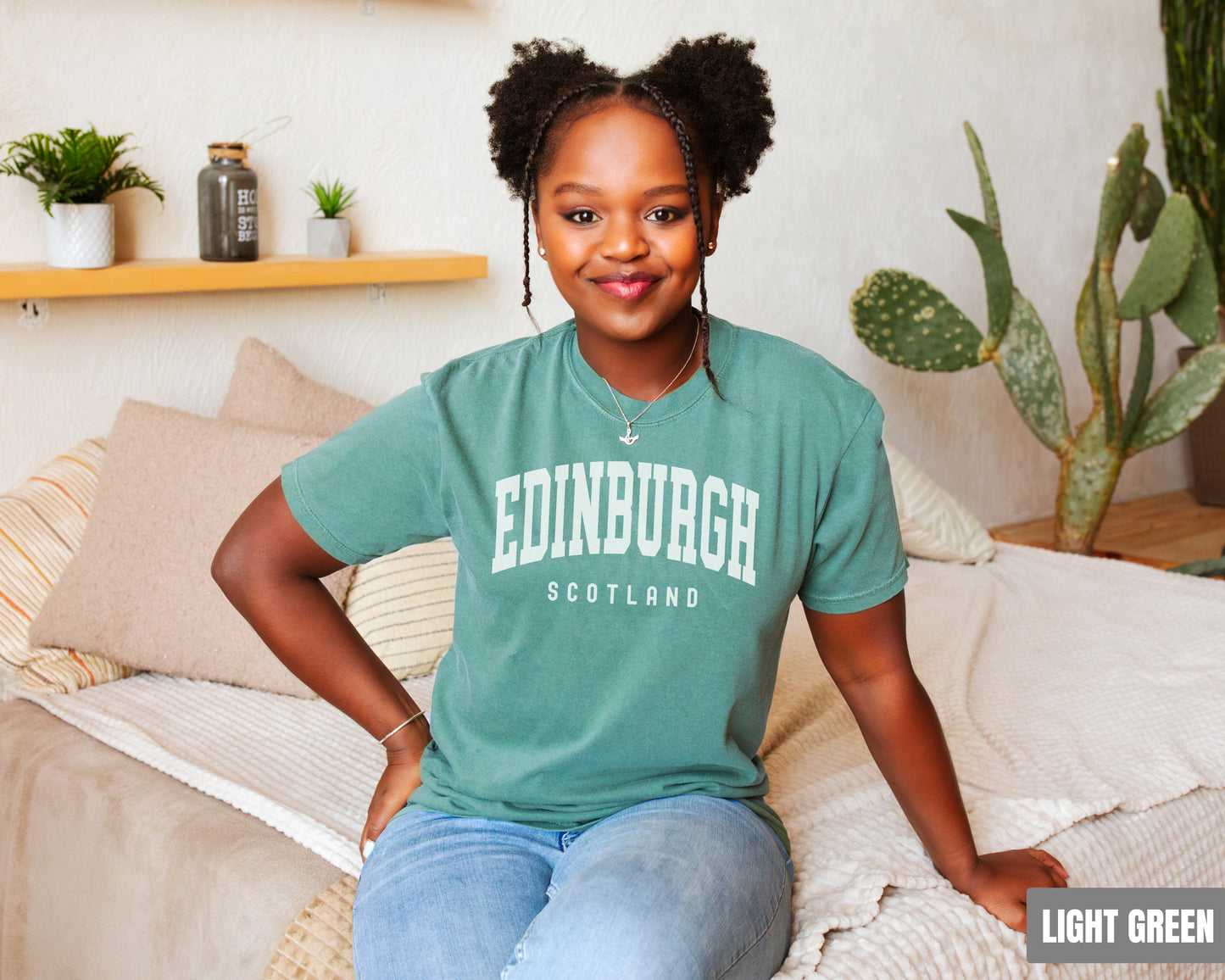 a woman sitting on top of a bed wearing a green shirt