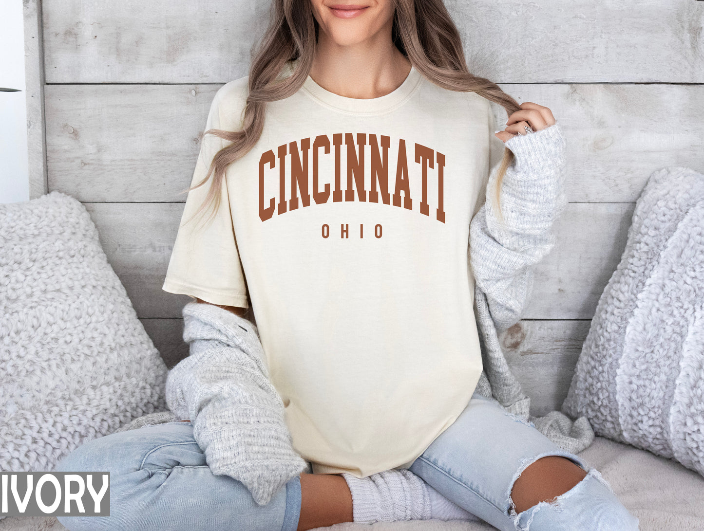 a woman sitting on a bed wearing a shirt that says cincinnati