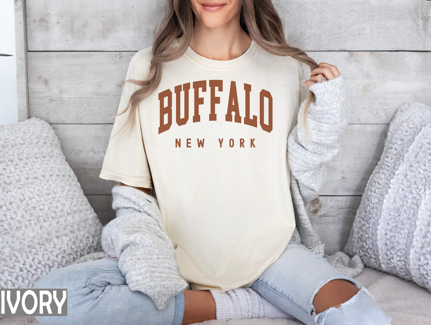 a woman sitting on a bed wearing a buffalo new york shirt