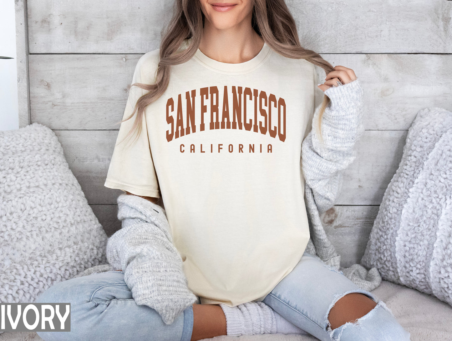 a woman sitting on a bed wearing a san francisco california t - shirt