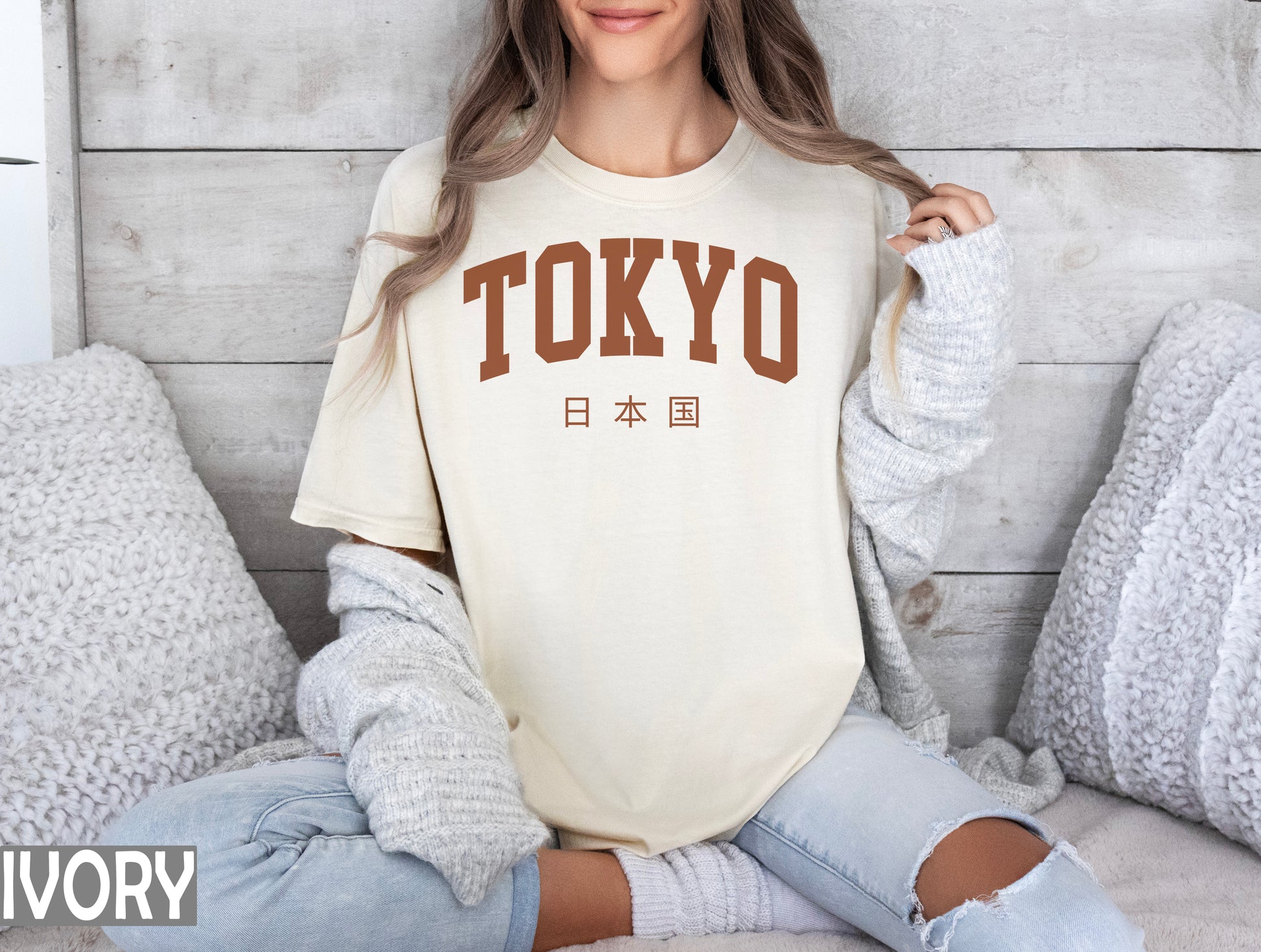 a woman sitting on a bed wearing a shirt that says tokyo