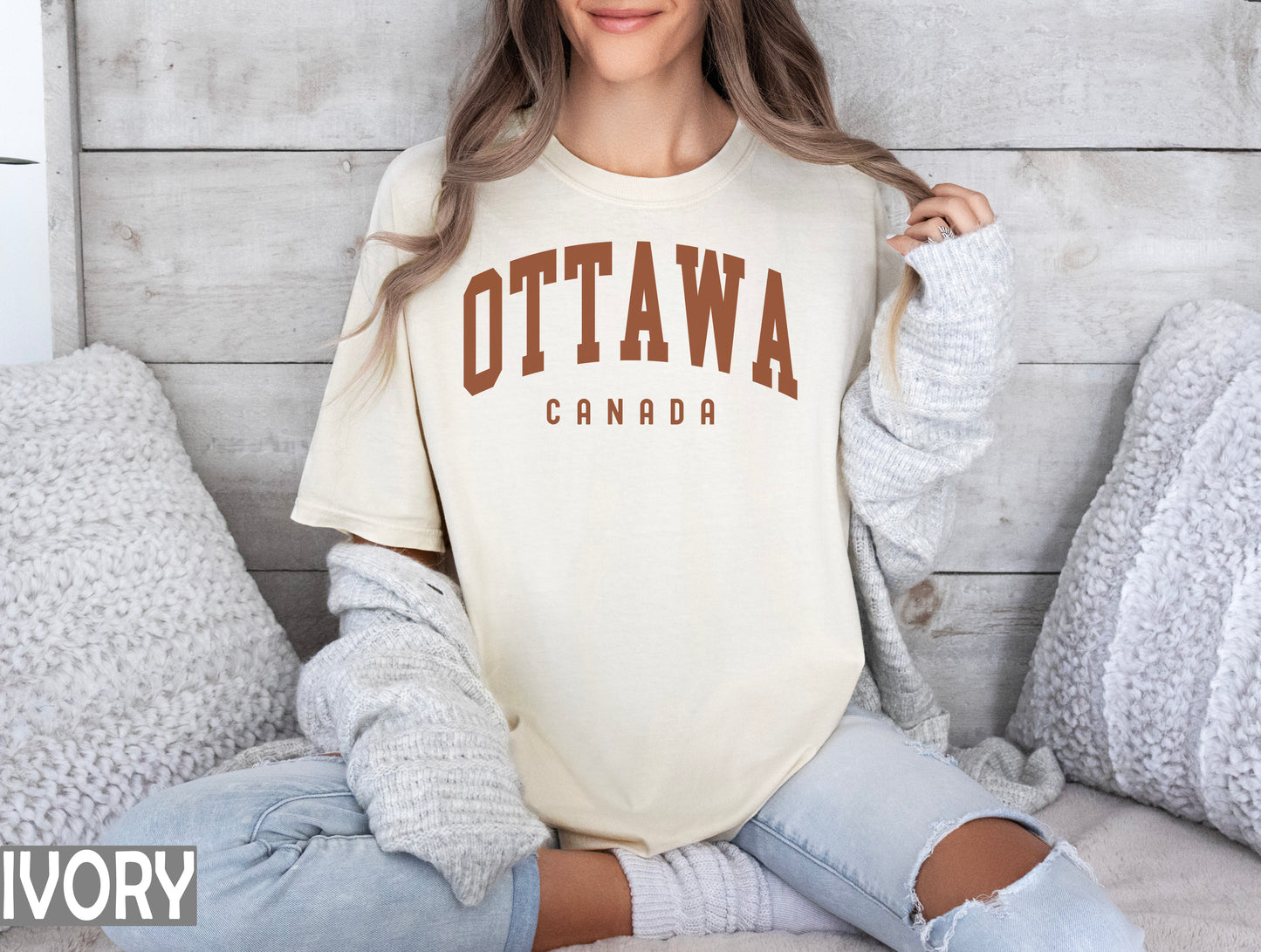 a woman sitting on a bed wearing a ottawa shirt