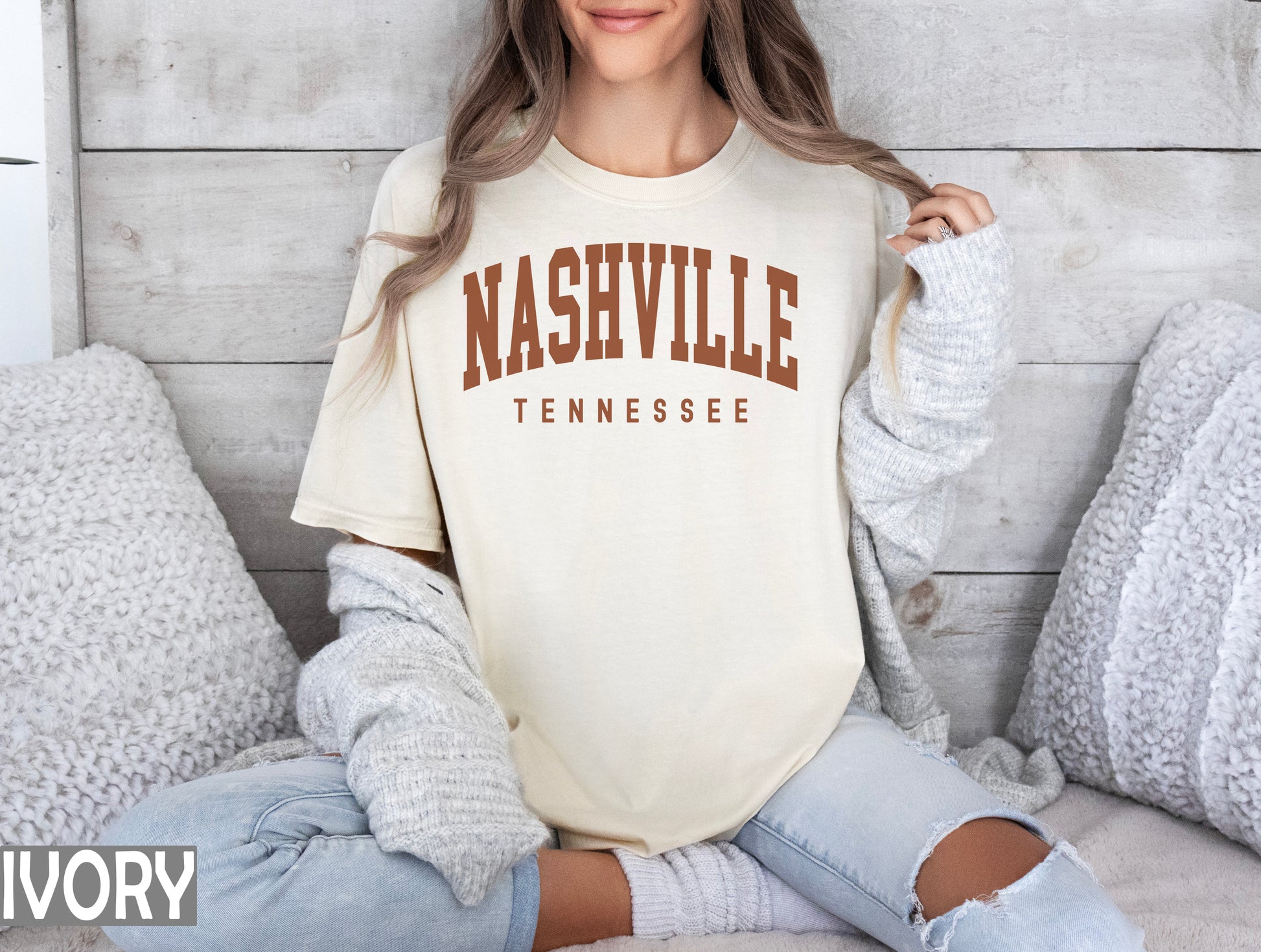 a woman sitting on a bed wearing a nashville t - shirt