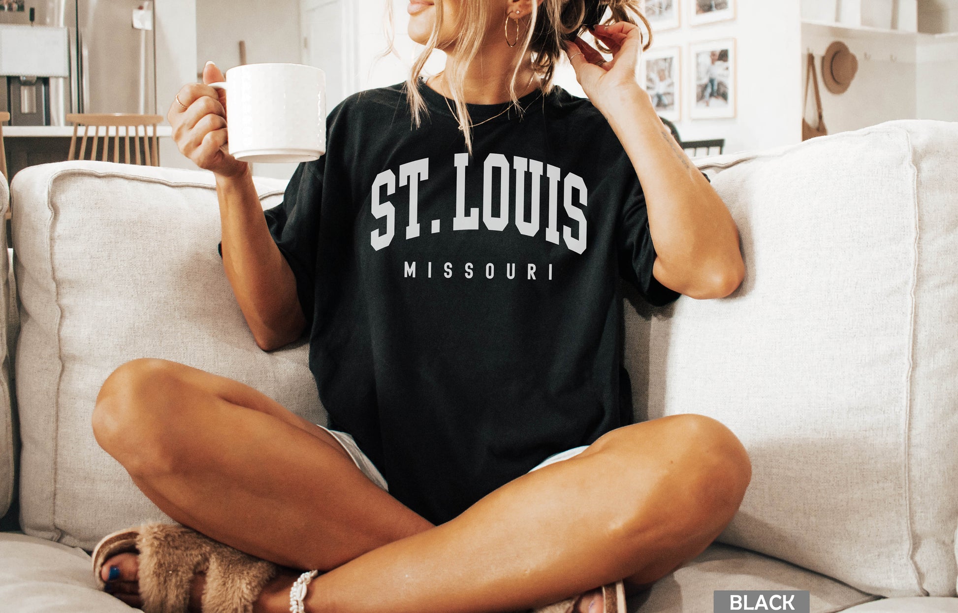 a woman sitting on a couch holding a cup of coffee