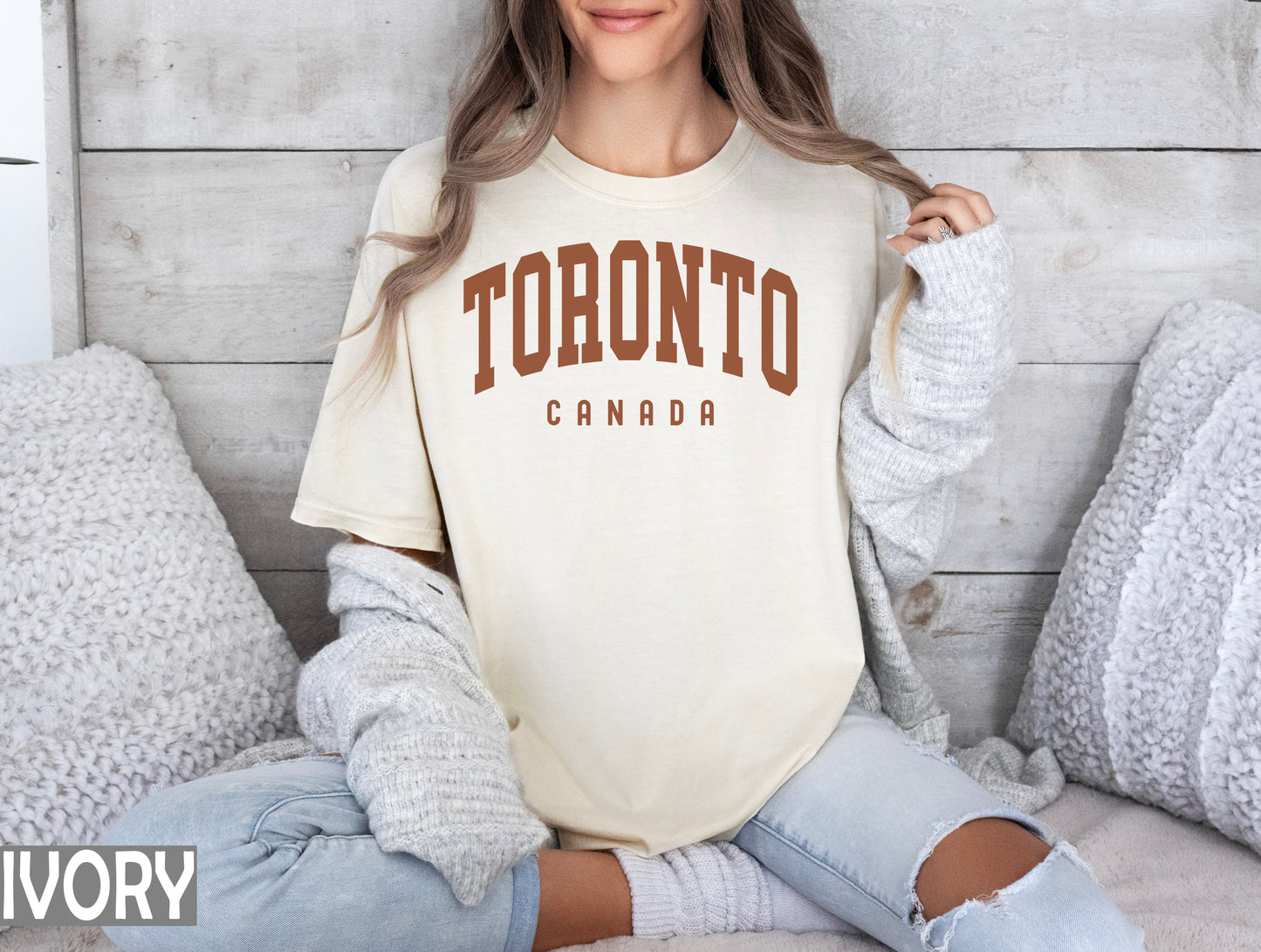 a woman sitting on a bed wearing a toronto t - shirt