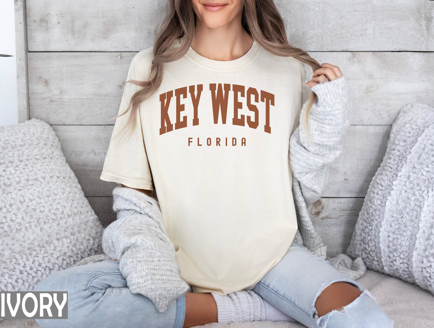 a woman sitting on a bed wearing a shirt that says key west florida