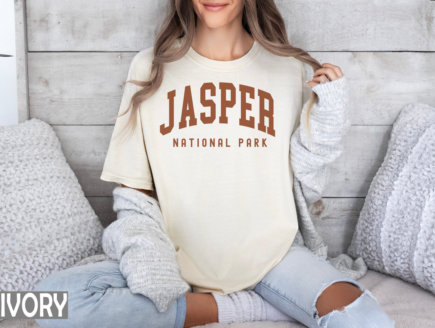 a woman sitting on a bed wearing a shirt that says jasper national park