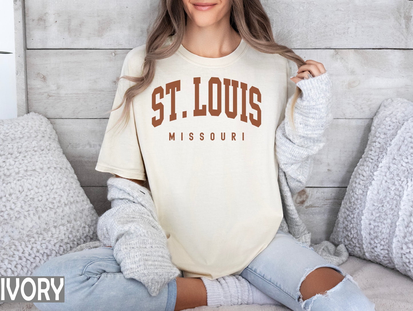 a woman sitting on a bed wearing a st louis shirt