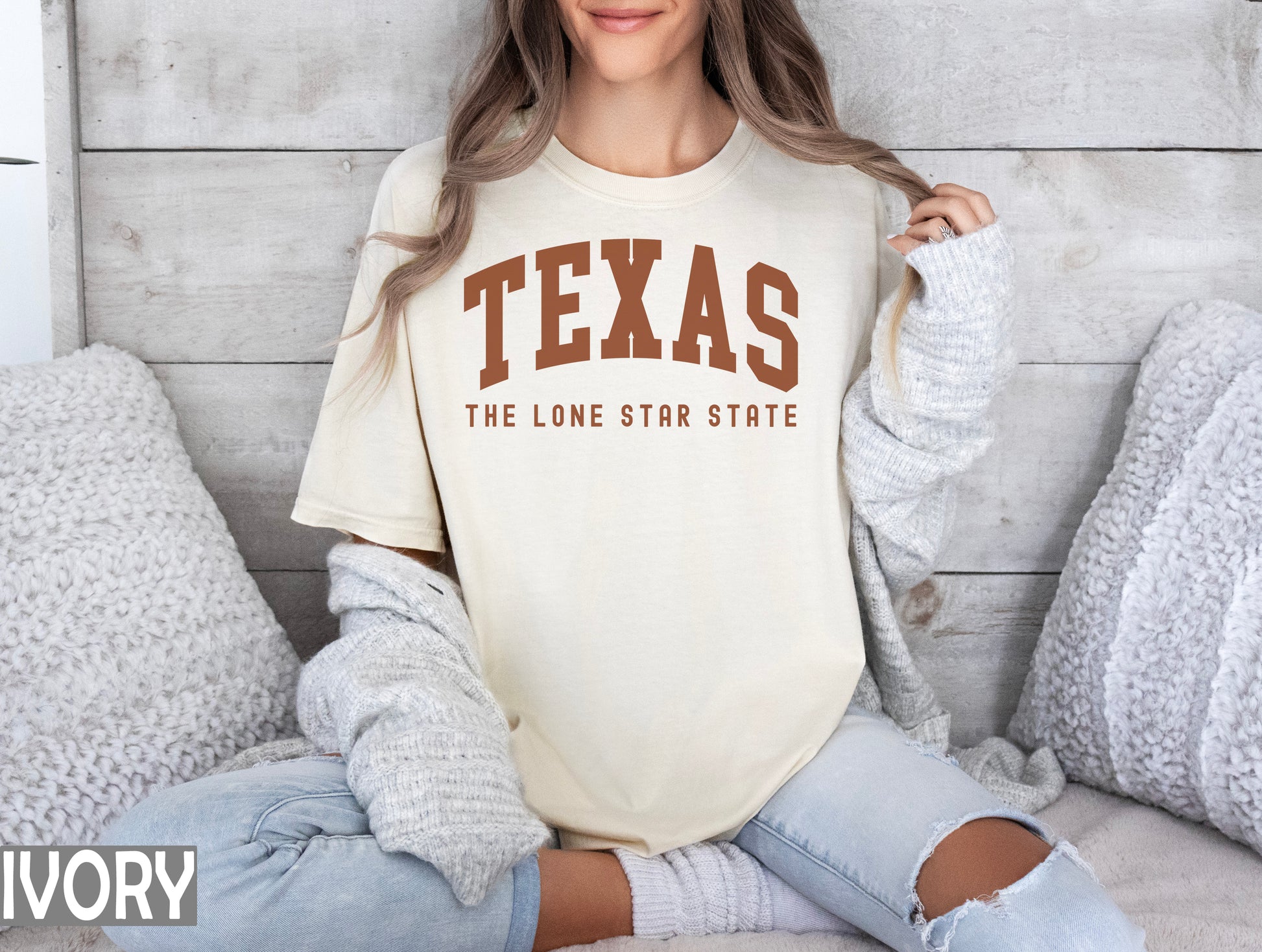 a woman sitting on a bed wearing a texas t - shirt