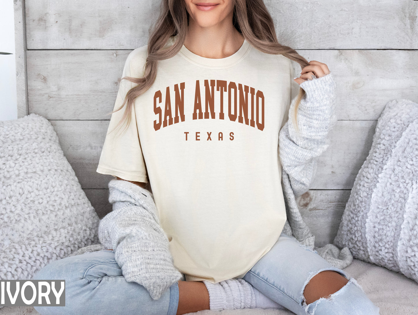 a woman sitting on a bed wearing a san antonio texas shirt