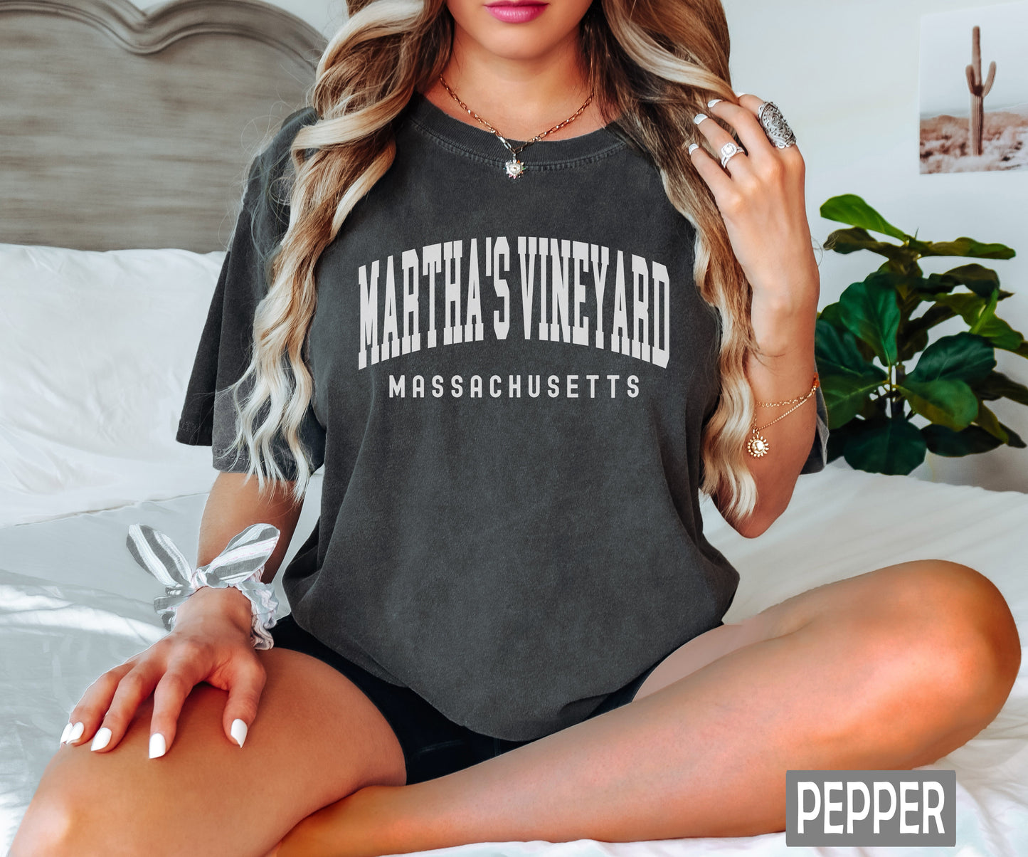 a woman sitting on a bed wearing a shirt that says martha's vineyard