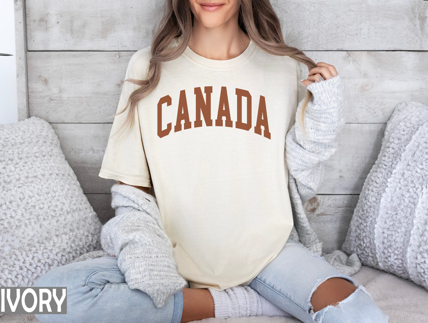 a woman sitting on a bed wearing a shirt that says canada