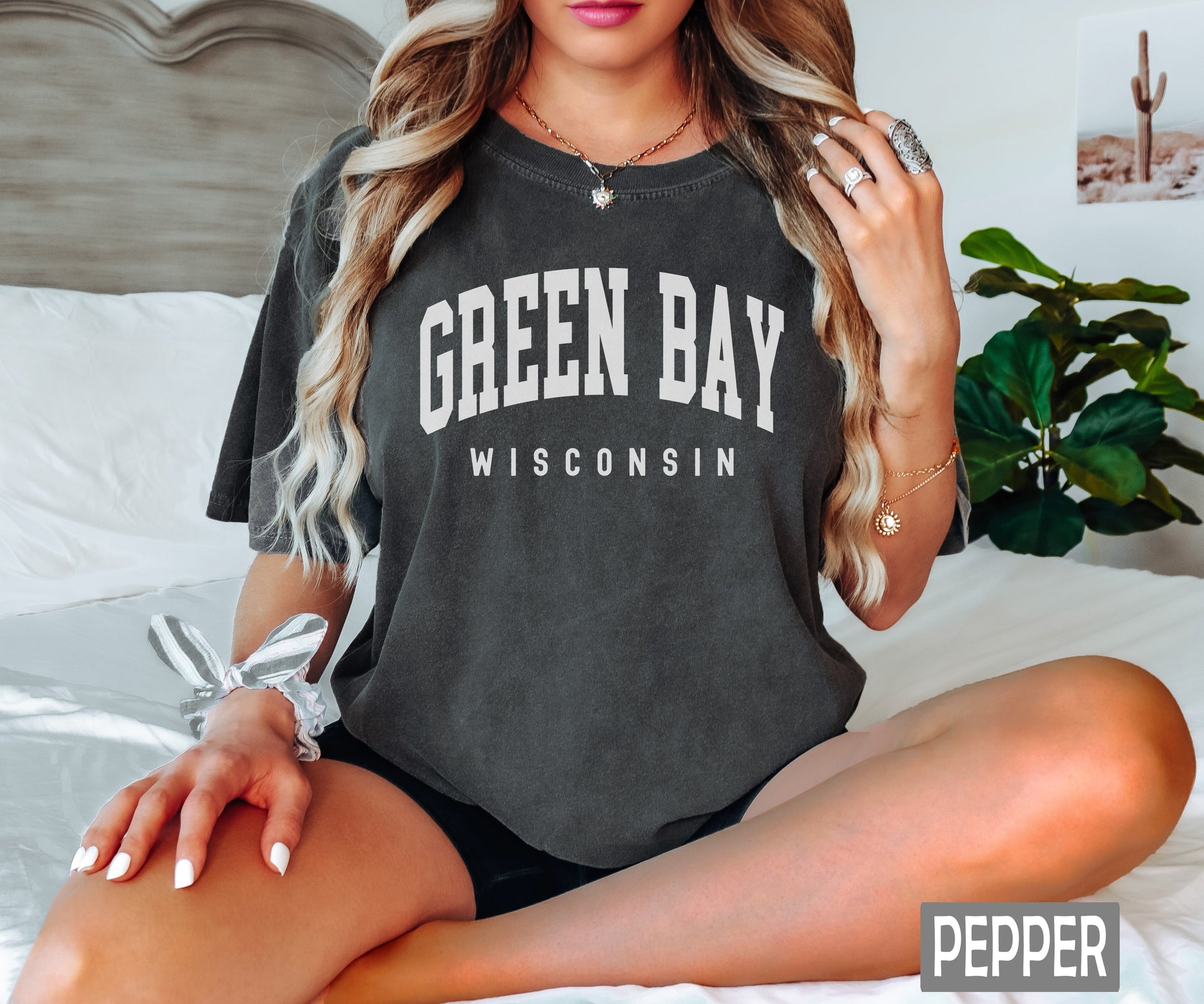 a woman sitting on a bed wearing a green bay wisconsin shirt