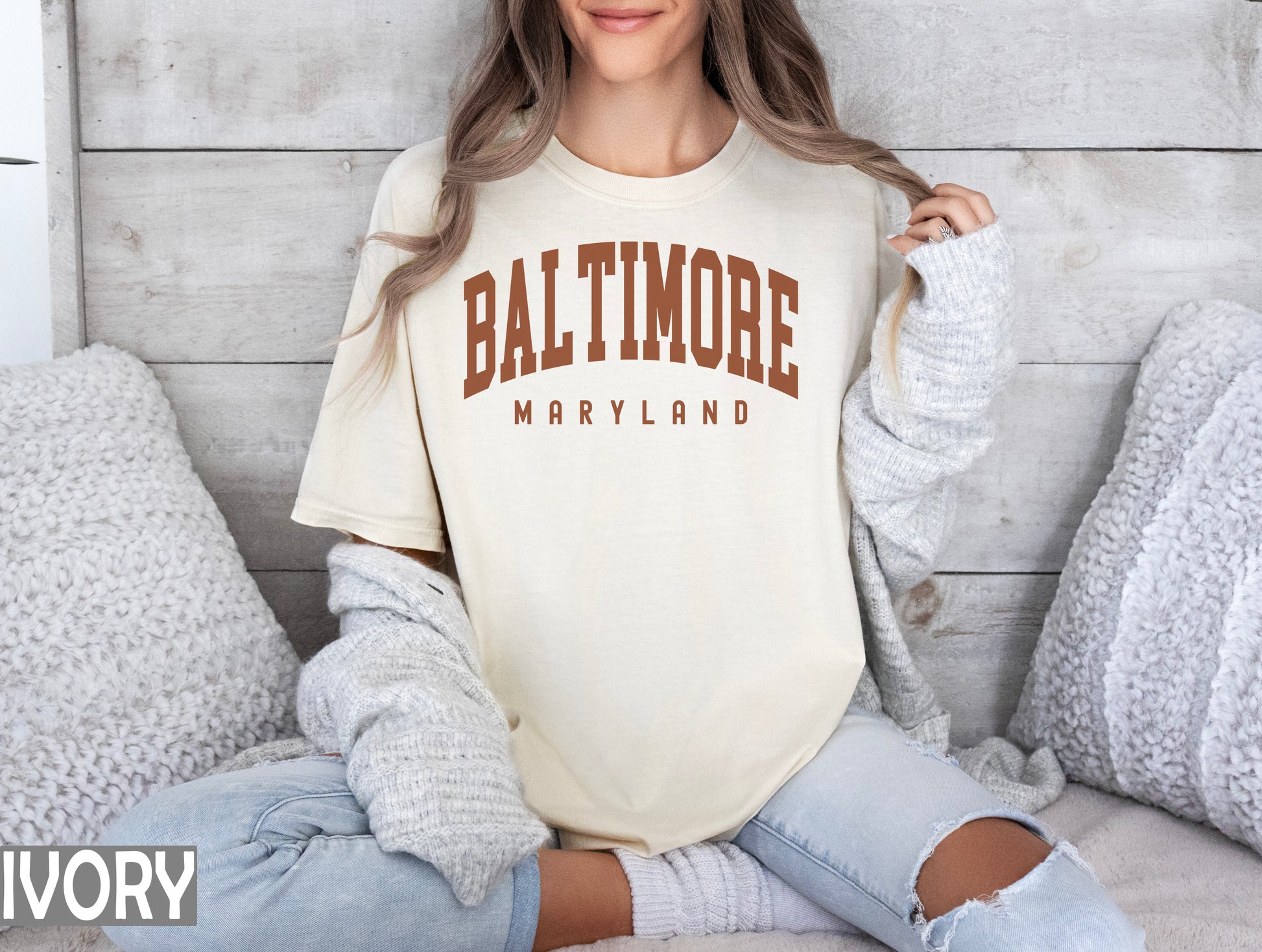 a woman sitting on a bed wearing a shirt that says baltimore