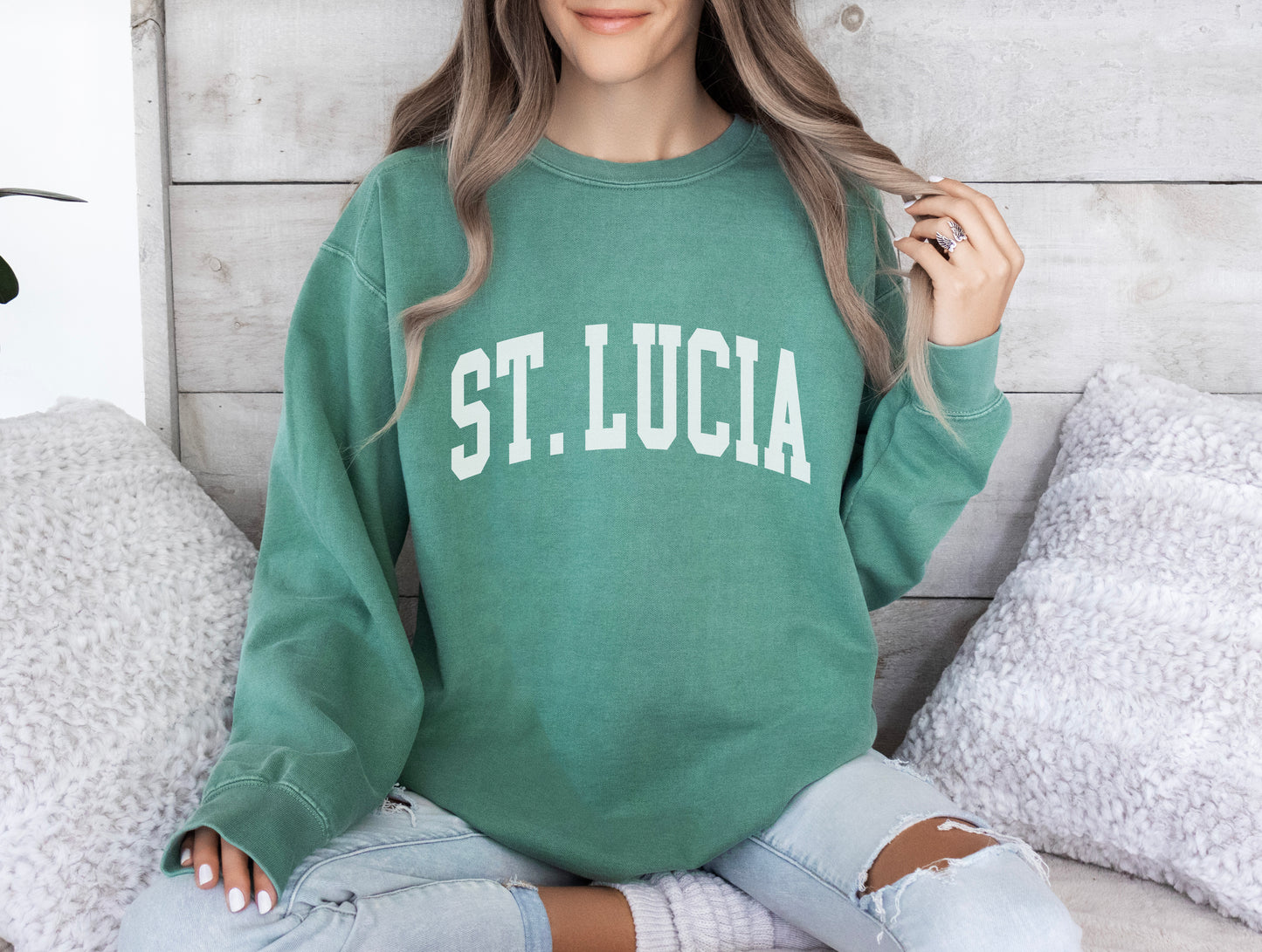 a woman sitting on a bed wearing a green sweatshirt